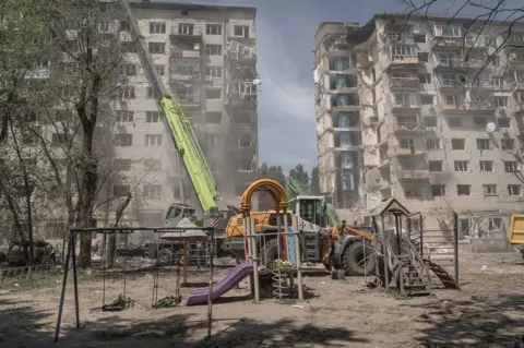 After a night of terror in Kyiv, the search for dead goes on A cruise missile destroyed an entire section of a nine-storey residential building in Kyiv. Flowers were laid by mourners in the playground beneath.