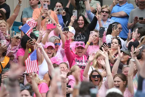 Karen Read found not guilty of murdering police officer boyfriend Boston Herald via Getty Images Supporters cheer outside court as Karen Read is acquitted of murder and manslaughter charges. Some are wearing pink shirts and hats and others are holding the US flag.
