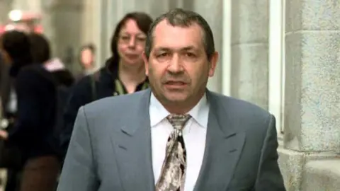 Police make renewed call over John 'Goldfinger' Palmer murder PA Media John Palmer in a grey suit, white shirt and tie walking towards the camera outside the Old Bailey in 2001.