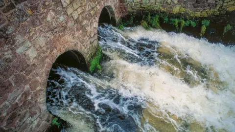 Bosses' bonuses banned at six water companies Getty Images Waste water from large sewage treatment plant flowing directly into a river