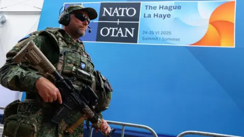 Leaders arrive at Hague summit as Nato chief Rutte flatters Trump Reuters An armed soldier stands in front of a blue Nato logo