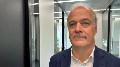 Ketamine swapped for salt as smugglers exploit Europe loophole in booming market Headshot of Marc Vancoillie, head of Belgium's central directorate of drugs. He has short grey hair and is wearing a navy suit jacket and white open-necked shirt. He is standing is an office corridor.