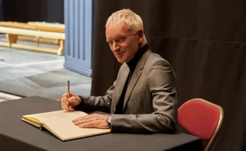 Governments have neglected the North East for decades North Tyneside Council Sting smiling, in grey suit signing book