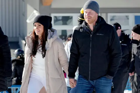 Can the Beckham brand survive reports of family feud? Getty Images Meghan and Prince Harry, wrapped in winter clothing and holding hands, at an 2024 outdoor event in Vancouver for the Invictus Games