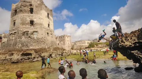 Somalia's construction boom in Mogadishu gives women high ambitions AFP / Getting Images Children dive, play and swim in front of the ruins of an old building on the seashore of Hamarweyne district in Mogadishu