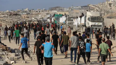 Hamas official says Gaza mediators intensifying ceasefire efforts Reuters Palestinians gather to collect food from aid lorries guarded by armed members of local clans in Beit Lahia, northern Gaza (25 June 2025)