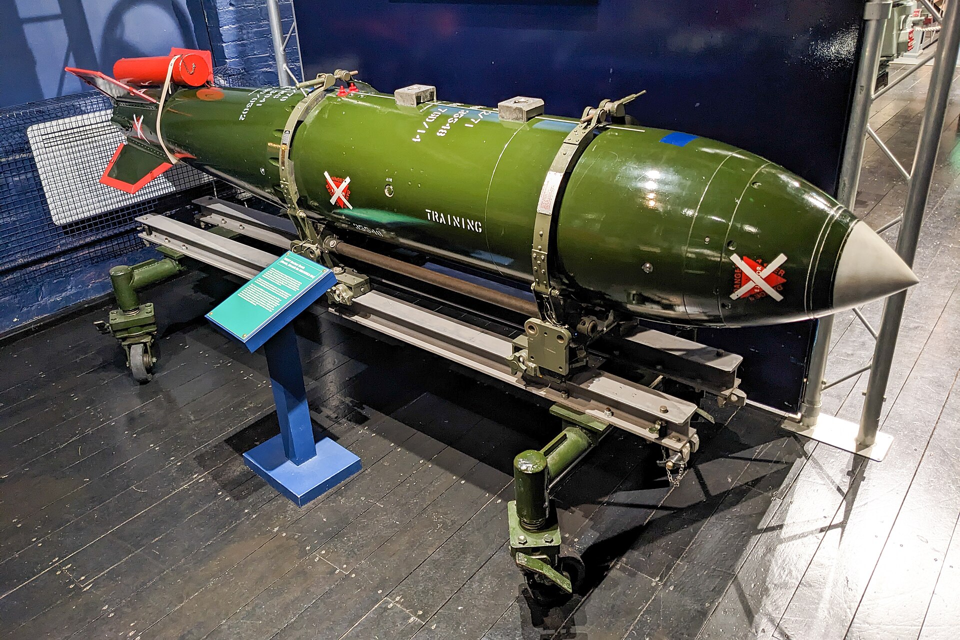 A mostly green coloured bomb around 3 metres long, marked with the word 