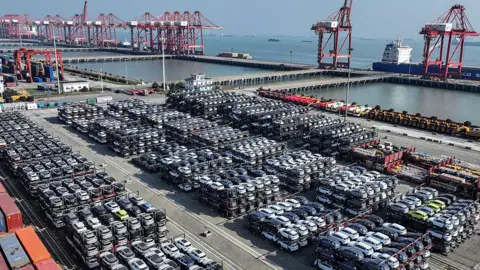 How China made electric vehicles mainstream Getty Images Rows and rows of stacked cars at a port in Suzhou, in eastern China's Jiangsu province, on April 7, 2025. The loading docks and cranes are visible, and beyond them the ocean.