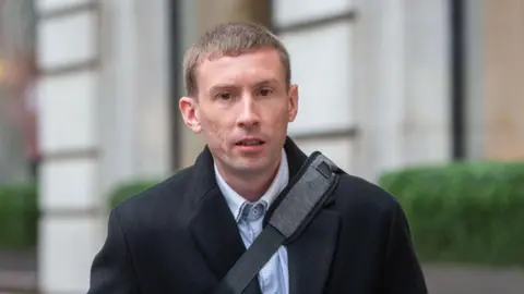 Insufficient action on compensation, say MPs Alamy Chris Head, pictured outside wearing a black coat with a black bag strap across his body