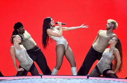 Dua Lipa brings out Jamiroquai at emotional Wembley debut Getty Images Dua Lipa leans back while singing, as dancers frame her on stage