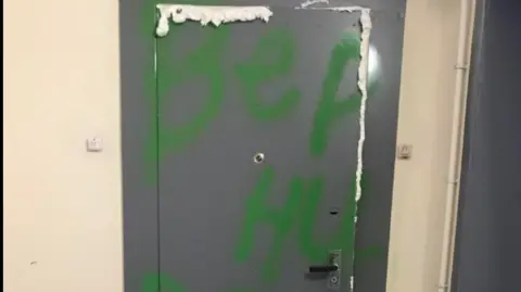 How Belarus dissidents in exile abroad are pursued and threatened A grey door daubed with green paint is surrounded by foam.