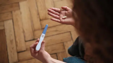 MPs to vote on decriminalising abortion Getty Images A woman holds a pregnancy test in one hand and a pill in the other