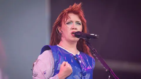 CMAT says she still gets abuse after viral song Getty Images CMAT, dressed in a bright and shiny blue top, sings during day three of Glastonbury festival 2025 at Worthy Farm in Pilton, Somerset.