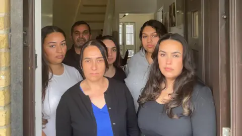 A neighbour threatened dad with a knife BBC Dilara, her father Ecevit, and family pictured in the doorway of their home