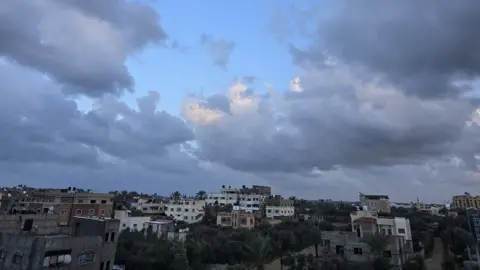 I feel like the life I had before the war was all made up A landscape shot of buildings beneath a cloudy sky