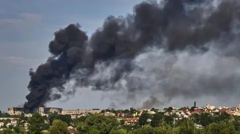 Russia launches biggest drone attack on Ukraine's Kharkiv EPA Black smoke billows out over the Kharkiv skyline from a large building that appears bombed out.