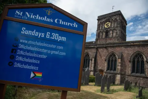 A preacher asked me out and then started stalking me A blue sign with service information and contact details in the foreground, with St Nicholas Church in Leicester's old stone building in the background.