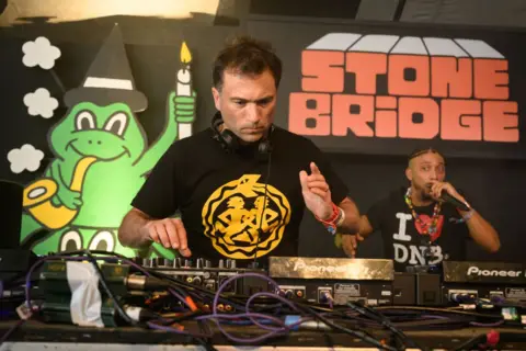 Emily Eavis on Glastonbury's magical 'Thursday Feeling' Getty Images Ros Atkins DJs at Glastonbury's Stone Bridge venue in 2024