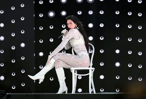 Dua Lipa brings out Jamiroquai at emotional Wembley debut Getty Images Dua Lipa dressed in a white lace bodysuit performs a song while sitting on a chair