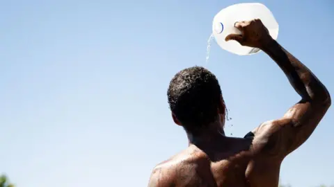 Why we need 'revolutionary' cooling tech Getty Images A man pours water from a large container on his head on a sunny day.