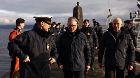 Shaping Scotland's priorities for years to come No 10 Downing Street Prime Minister Sir Keir Starmer and Defence Secretary John Healey visited a Vanguard-class submarine in March. They are on board the deck in thick parkas. A naval officer in full outdoor uniform is speaking to them.