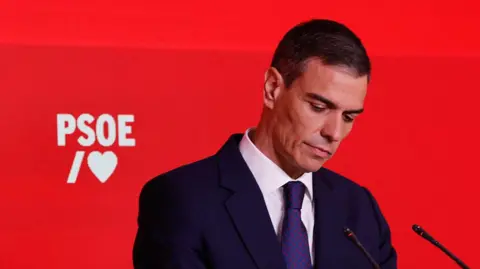 Spain's Sánchez sorry for corruption scandal as opposition calls for resignation OSCAR DEL POZO/AFP A man in a dark suit and tie looks down with a red backdrop