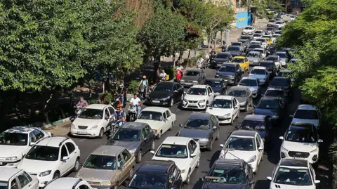Trump's order to leave Tehran adds to fear as Iranians share 'last photo of home' Getty Images Vehicles wait in lines of traffic as people queue to get out of Tehran through road in the west of the city on 15 June 2025