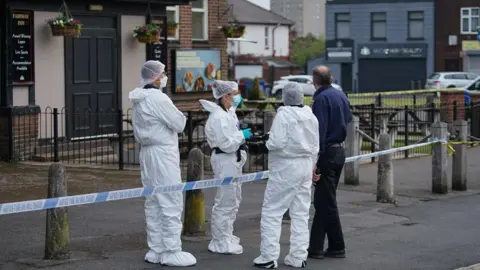 Teens arrested on suspicion of murder as boy, 14, stabbed to death JMG Press Three forensics officers talking to a man dressed in black trousers and navy shirt at a police cordon around a pub.