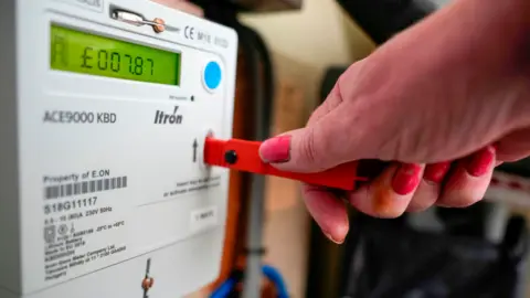 What next for gas and electricity bills and can I fix? Getty Images Hand on a key being inserted into a prepayment meter with a display showing £7.87 left in credit.