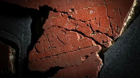 Huge archaeological puzzle reveals Roman London frescoes Tony Jolliffe/BBC News A close up of piece of red plaster, made up of several smaller pieces, with the letters F E C I T in capitals clearly visible with a line drawn in a square around three sides of the word. The left hand side of the plaster, where the name of the person or group who made the piece of art should be, is missing.