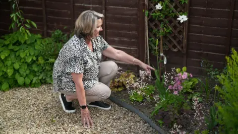 More pets being put down due to rising costs, BBC told Caroline is in her garden. She is pointing at the place where her cat Ozzie is buried
