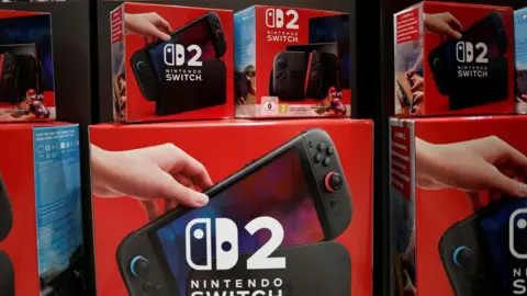 Video games cost a whole day's wages say fans, as prices rise Reuters Red boxes of Nintendo Switch 2 consoles are piled up in a shop window. The box shows the console itself with along with the Nintendo Switch logo.