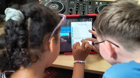 Bradford families urged to sign up to 'holiday hunger' clubs YACAD Two children working on a tablet computer, doing some sound editing.