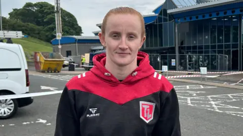 Families hid in attics during 'race motivated' disorder, says chief constable An athlete is standing outside a leisure centre with temporary fencing around the entrance. A skip is in the background and police tape has been put up.