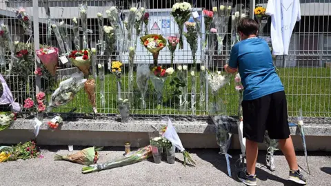 School killings leave stunned Austria and France searching for answers AFP A boy hangs flowers on the fence of his school
