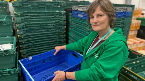 Lincoln food bank at 'breaking point' due to low stock BBC The photo shows a lady with a neutral expression looking at the camera. She is wearing a green hoodie, and is holding an empty blue crate. Behind her are stacks of crates about 5ft (1.5m) high which are also all empty.