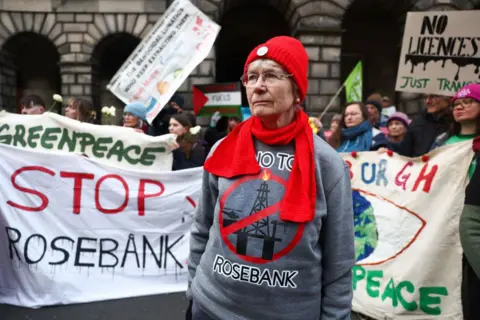 New emissions guidance published for North Sea oil and gas projects Getty Images Protesters outside Edinburgh's Court of Session with white banners saying "stop Rosebank". In the foreground is a woman with glasses, a red hat and scarf, and a grey jumper with an anti-Rosebank slogan