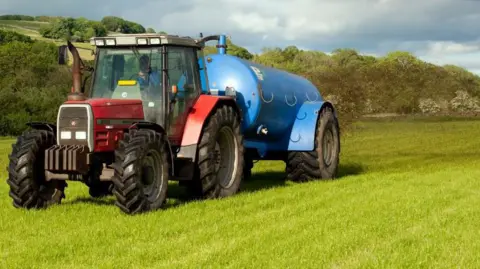 Warning over 'dirty secret' of toxic chemicals on farmers fields Getty Images A red tractor pulls a blue trailer as it spreads slurry on a field.