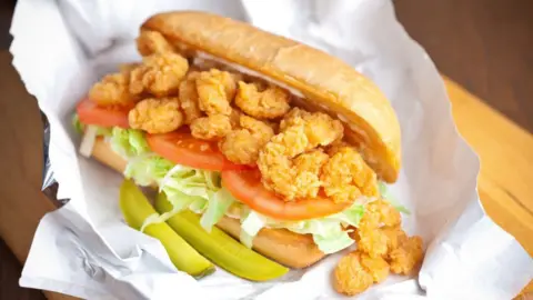 Japanese fruit sando hits high streets Kcline/Getty Images A po' boy sandwich, made with fried shrimp, tomato, lettuce, pickles and sauce, is served on a wrapper on a wooden table