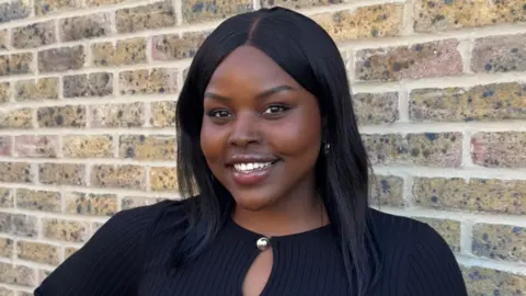 Asos customers banned over returns say it is 'slap in the face' A woman with black hair smiles in front of a light brick wall.