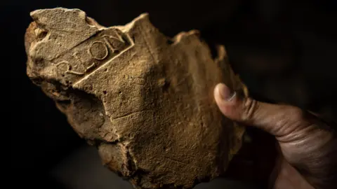 Huge archaeological puzzle reveals Roman London frescoes Tony Jolliffe/BBC News A close up of a broken piece of light brown stonework. Clearly visible are the remnants of some of the letters that have been imprinted in the plaster as it dried - R-L-O-N. It stands for Procurator of Londinium and shows that the building it was part of was a civil building in the growing city.