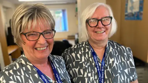 Behind the scenes at a GP 8am scramble BBC Two GP receptionists Jayne Bond and Sandra Brewster smiling ahead of their daily pressured stint answering the telephones first thing in the morning from patients trying to get an appointment from the surgery.