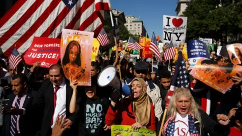 Trump's new ban dodges pitfalls faced by last attempt, experts say Getty Images A group of people march in the street in New York