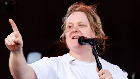 Lewis Capaldi in surprise Glastonbury return after releasing rousing comeback Getty Images Lewis Capaldi on stage at Glastonbury 2023 in a white T-shirt singing into a microphone with one finger pointing in the air