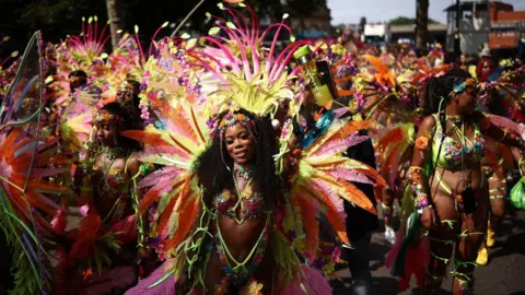 Future of Notting Hill Carnival 'in jeopardy' Getty Images Dancers in elaborate, brightly coloured feathered costumes take part in a vibrant street parade during Notting Hill Carnival.