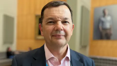 Hopes to open NHS ketamine clinic for treatment resistant depression Prof McIntosh looks directly at the camera. He has short brown hair and wears a pink open-necked shirt under a blue suit jacket
