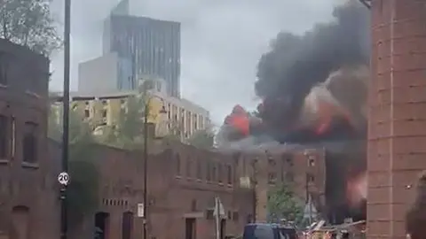 Residents evacuated from tower as blaze spreads X Flames and thick smoke rising from the roof and upper floors of the Hotspur Press building in Manchester, a Victorian-era red-brick warehouse.