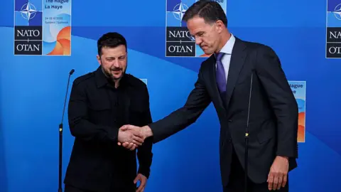 Leaders arrive at Hague summit as Nato chief Rutte flatters Trump Omar Havana/Getty Images The Ukrainian leader on the left wearing black shakes hands with the taller Dutch Nato Secretary General Mark Rutte against a blue background