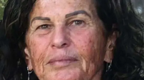 Israel recovers bodies of three dead hostages from Gaza The Hostages and Missing Families Forum An image of Ofra Keidar. She is looking directly at the camera, has black frizzy hair and earrings.