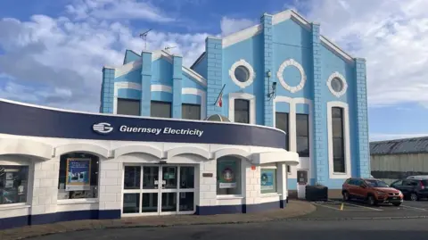 Why are electricity prices going up in Guernsey? A blue and white 20th Century industrial building with a Guernsey Electricity sign on it.